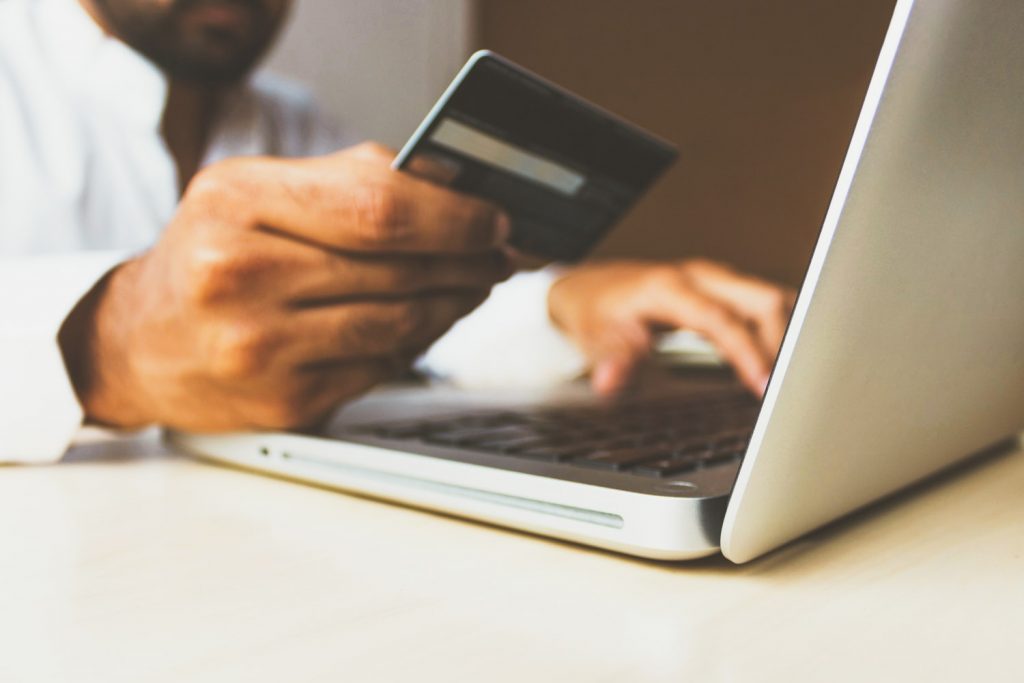 Man holding a credit card next to his laptop