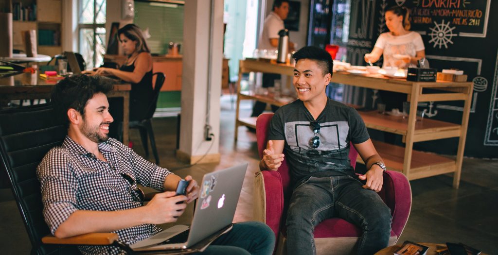 Two men on laptops smiling